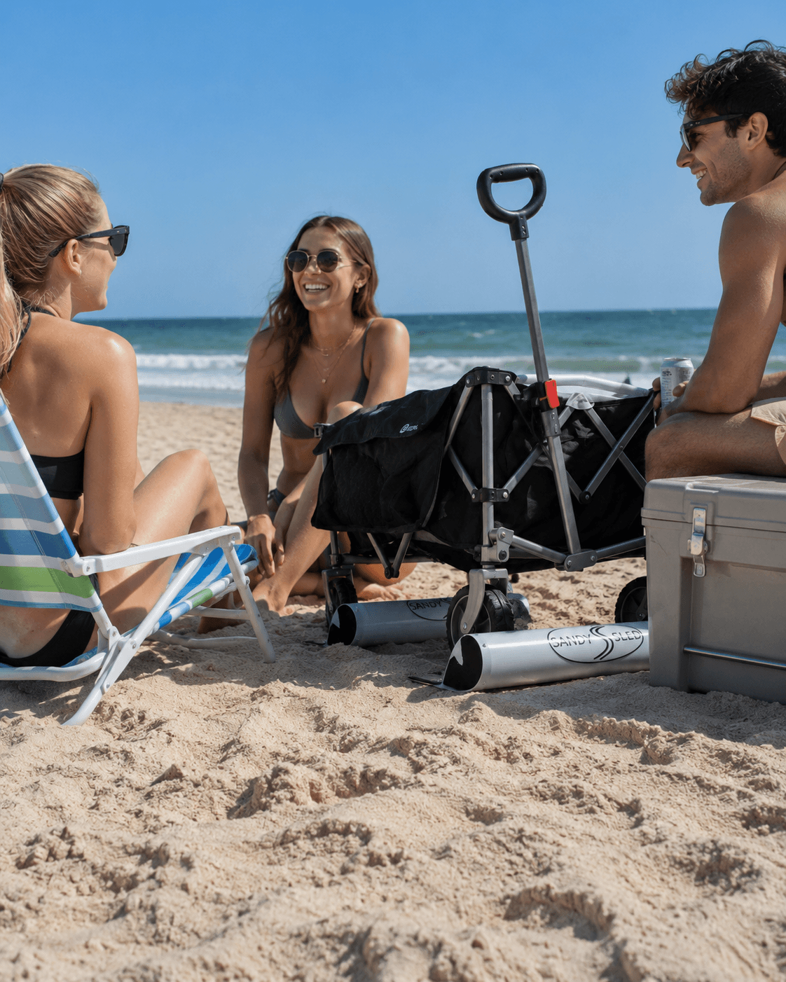 People using SandySled for beach gear on soft sand